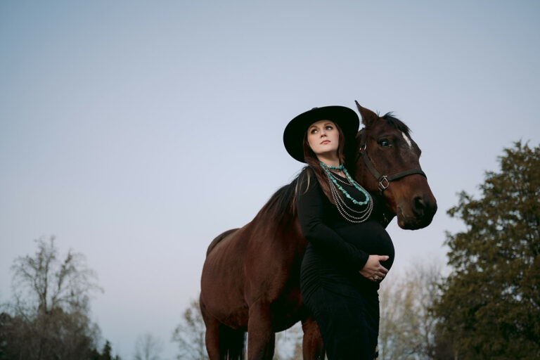 New mother holds her belly for a maternity photo with her horse.