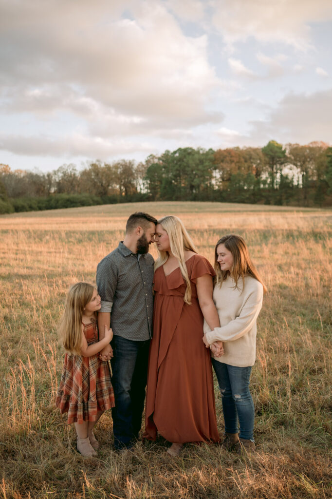 Family hugs each other in the field at sunset
